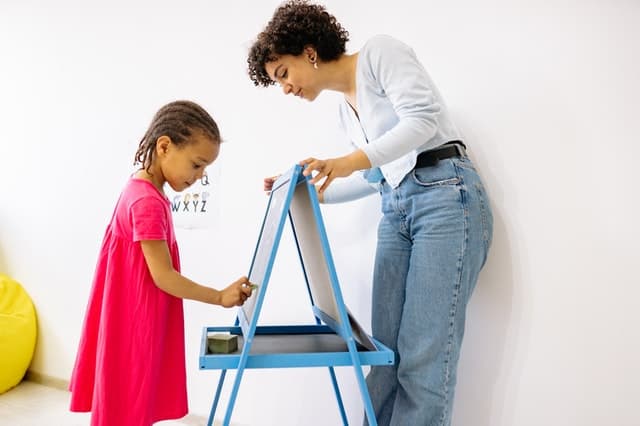 Child writing with an educator